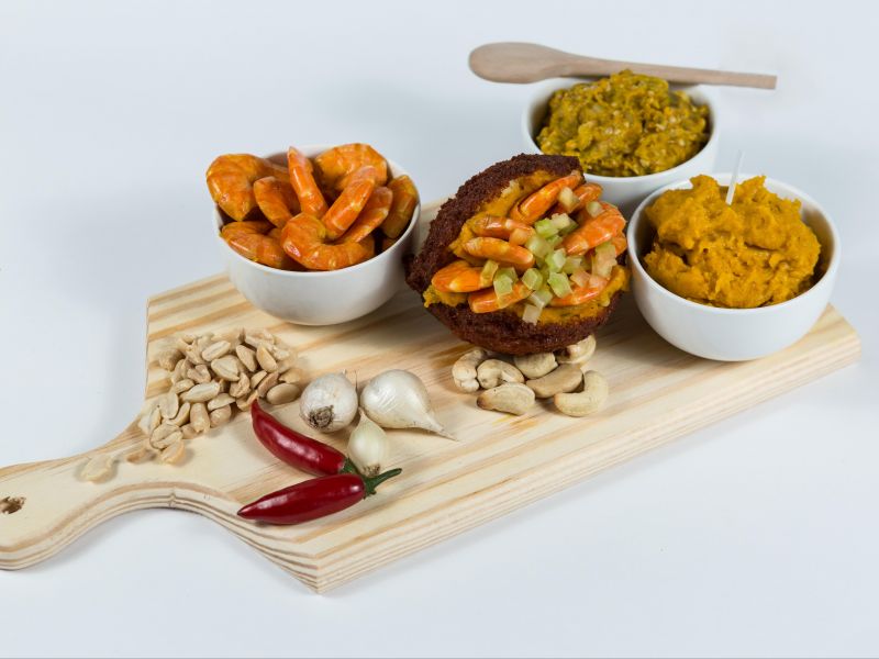 Tábua de madeira com vários ingredientes para a receita caruru como alho, pimenta e camarão