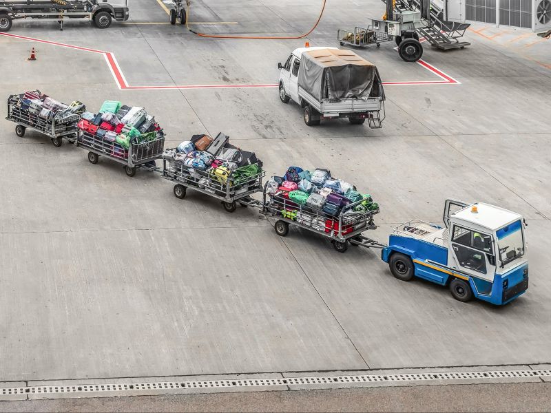 Carrinho que leva bagagens até as aeronaves, cheia de malas despachadas