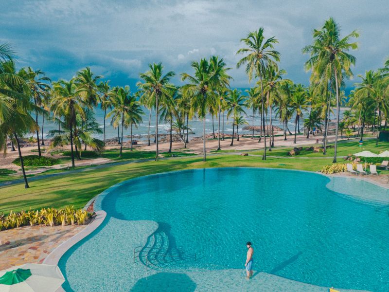 Homem em pé em uma das piscinas do Costa do Sauípe com o mar ao fundo