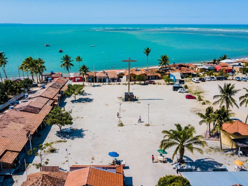 Imagem aérea da praça em Santa Cruz Cabrália com o mar azul cristalino ao fundo